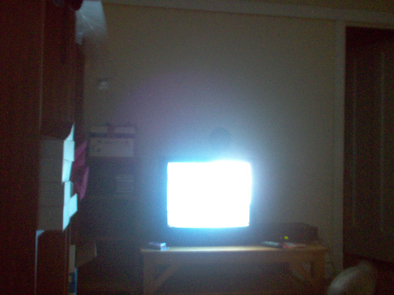 A blurred close-up of a CRT TV glow in a dark room